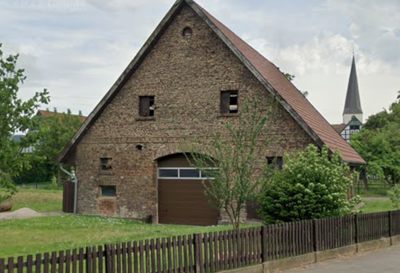 Beispiel: Ein altes Fachwerk-Scheunenhaus, dessen zwei Dachfenster und der Torbogen aussehen wie Augen, Nase und Mund – ein klassisches „Haus mit Gesicht“.